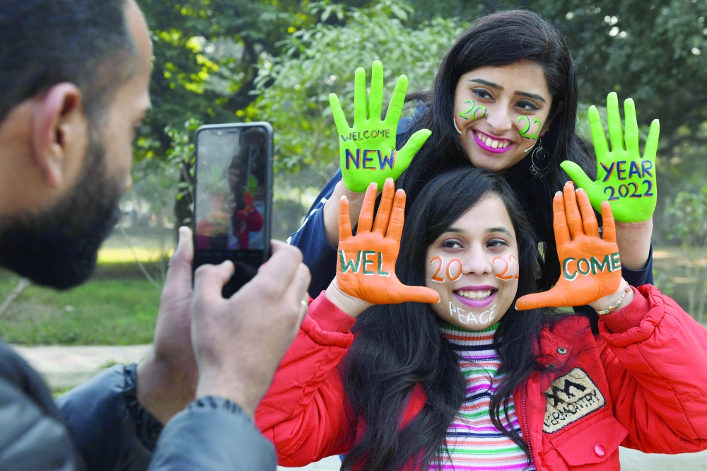 Young women pose for pictures after getting their hands and face painted ahead of New Year's Eve celebrations in Amritsar on Thursday.  -- AFP