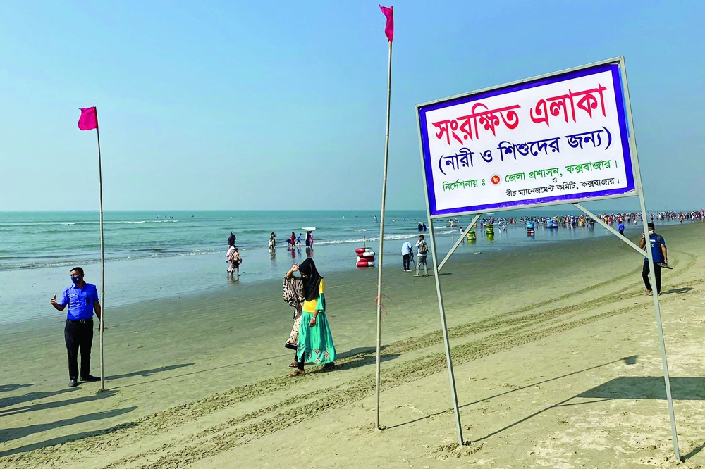 People walk past a signboard reading 'Reserved area for women and children as instructed by the district commissioner' along a beach in Cox's Bazar. -- AFP