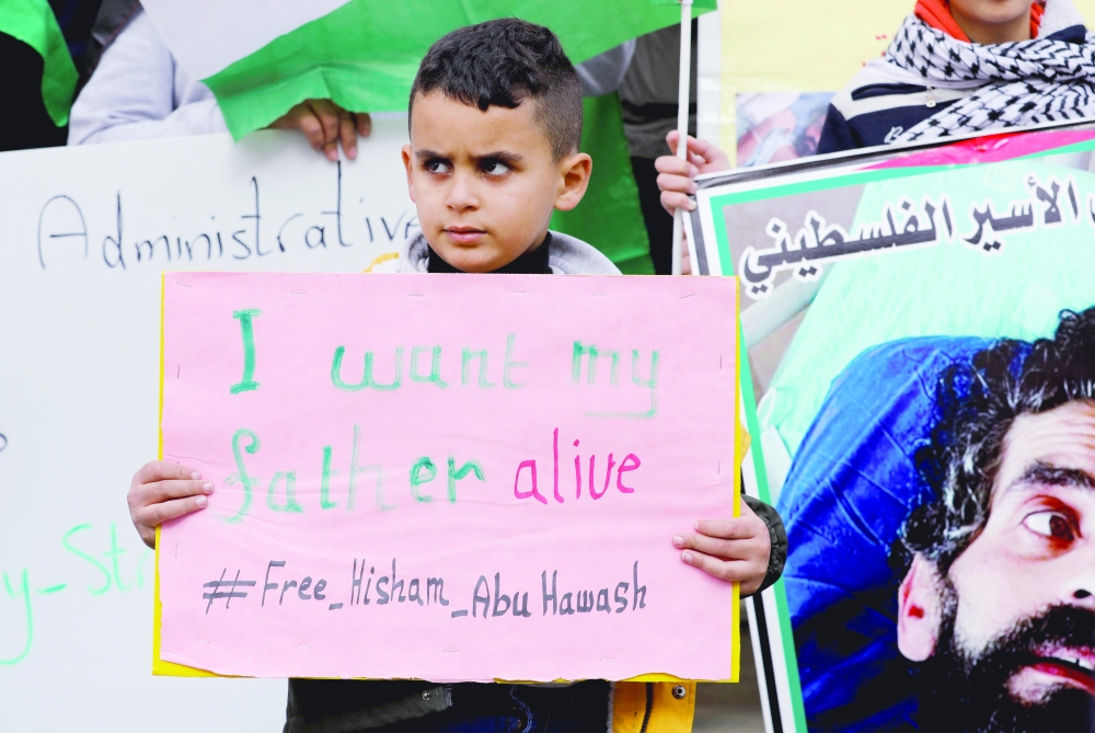 Izz, son of the hunger-striking Palestinian prisoner Hisham Aby Hawash, holds a sign during a protest in solidarity with him in Dura, in the Israeli occupied West Bank, on Sunday. - Reuters