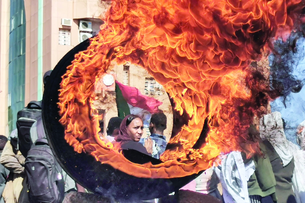 A demonstrator looks on from behind a flaming tire at a make-shift barricade erected during a protest demanding civilian rule in the “Street 40” of the Sudanese capital’s twin city of Omdurman on Tuesday. — AFP
