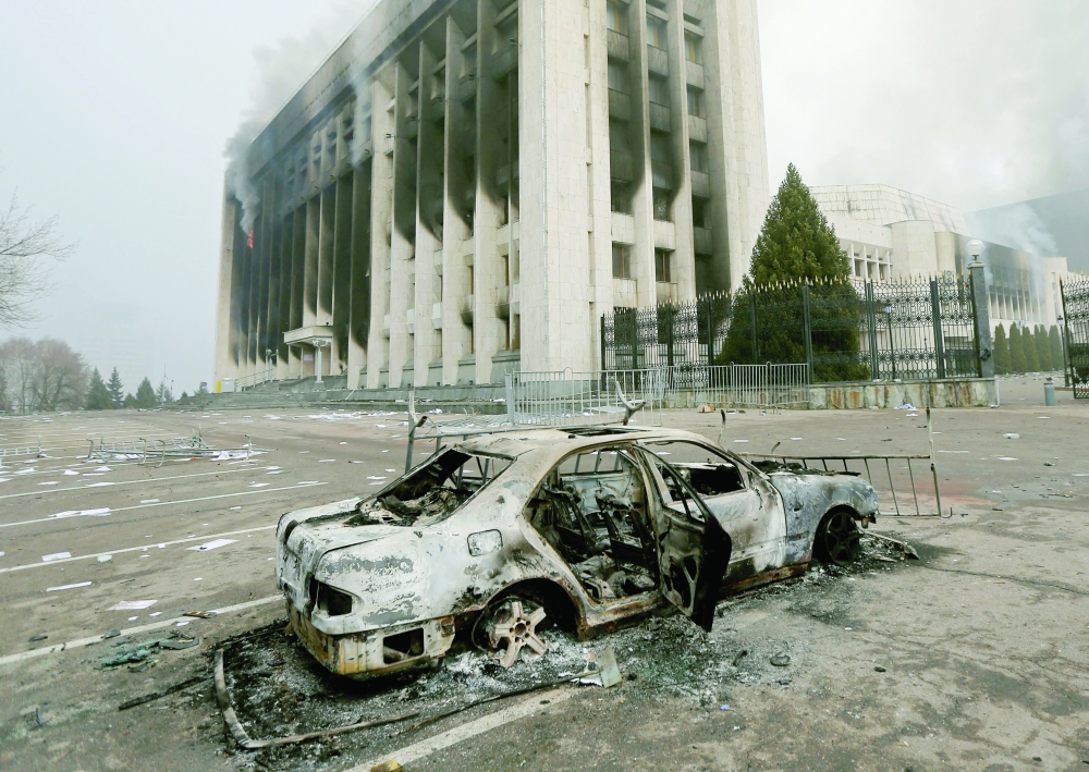 A burned car is seen in front of the mayor's office building which was torched during protests triggered by fuel price increase in Almaty. -- Reuters
