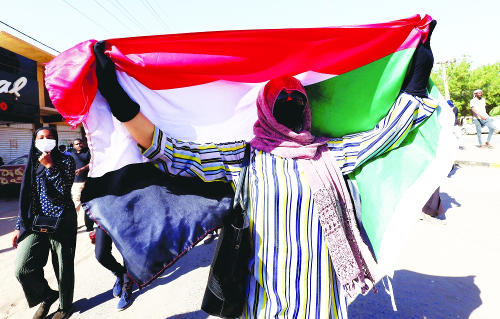 A person holds up Sudan's flag as protesters march during a rally against military rule in Khartoum. - Reuters file photo