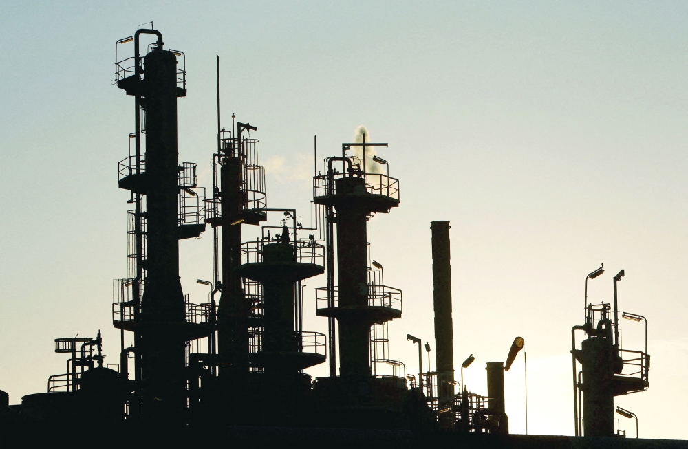 Towers and smokestacks are silhouetted at an oil refinery in Melbourne, Australia. — Reuters