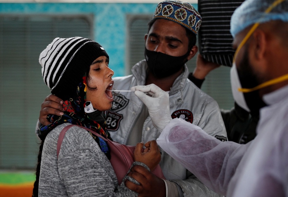 A health worker collects a swab sample from a woman during a rapid antigen testing campaign for the coronavirus disease (COVID-19), at a railway station in Mumbai, India, January 13, 2022. 
