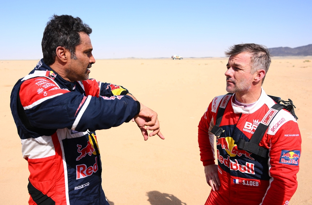 Toyota's driver Nasser Al-Attiyah of Qatar (L) speaks with French driver Sebastien Loeb during the Stage 11 of the Dakar 2022 around Bisha, Saudi Arabia, on January 13, 2022. (Photo by FRANCK FIFE / AFP)

