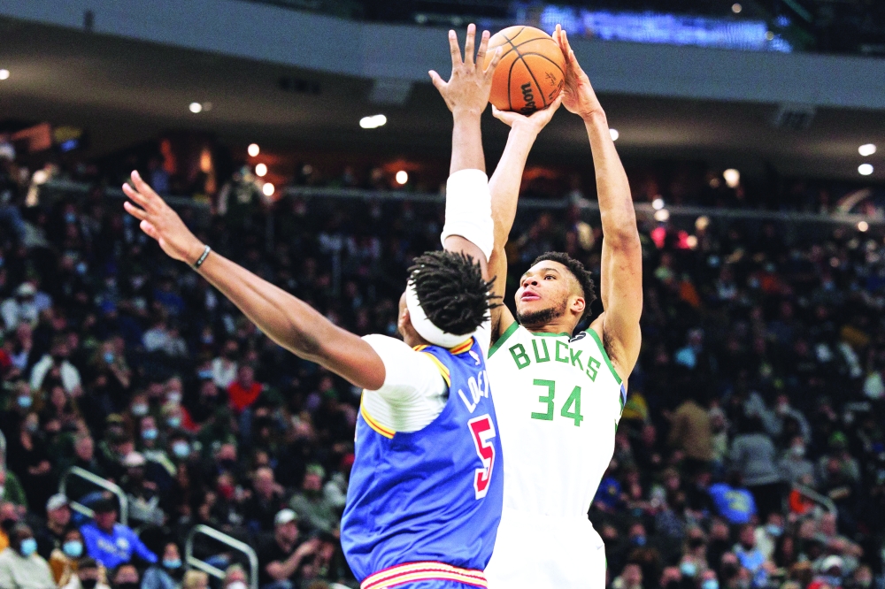 Milwaukee Bucks forward Giannis Antetokounmpo (34) shoots against Golden State Warriors forward Kevon Looney (5) during the third quarter at Fiserv Forum. -- USA Today Sports
