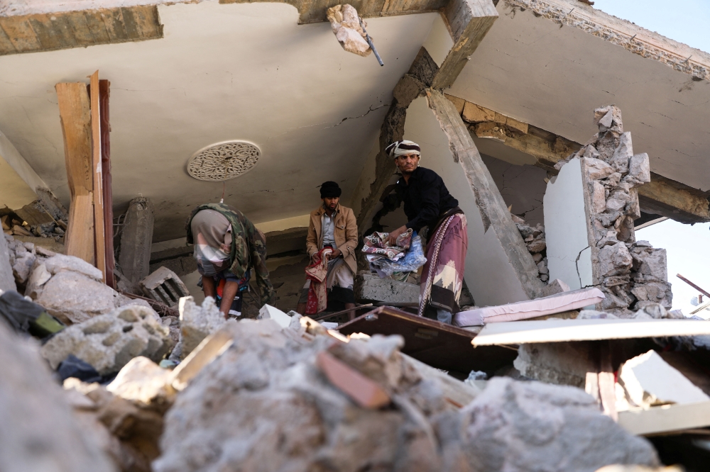 People remove the rubble under the collapsed roof of a house hit by Saudi-led air strikes in Sanaa, Yemen, January 18, 2022.