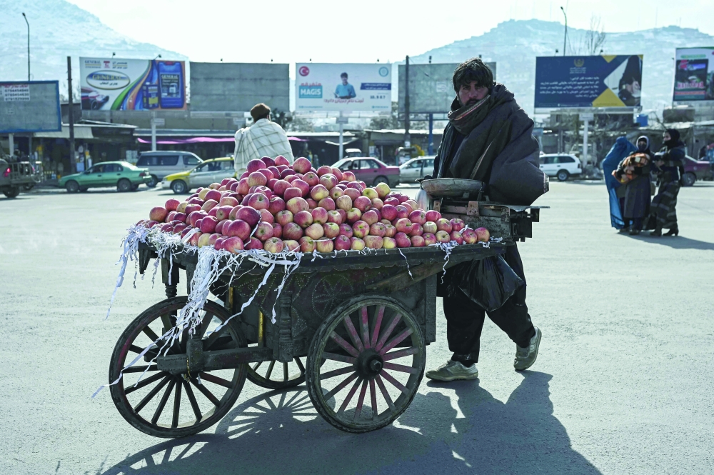 A vendor pushes his cart laden with apples on a street in Kabul. - AFP