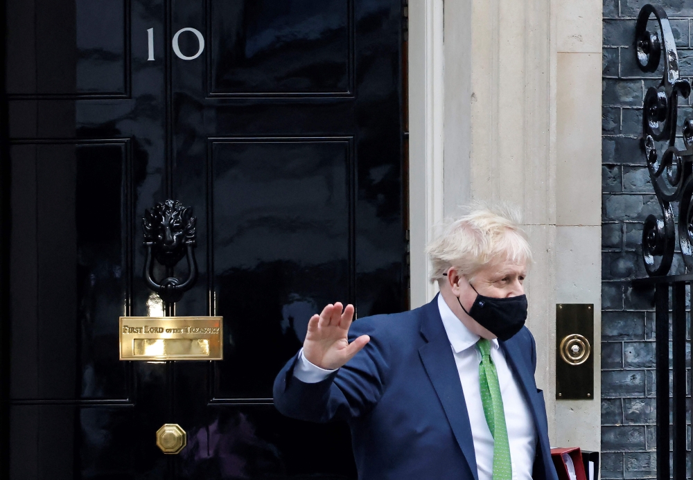 Britain's Prime Minister Boris Johnson, wearing a face-covering to help mitigate the spread of coronavirus, waves as he leaves from 10 Downing Street in central London on January 19, 2022.
