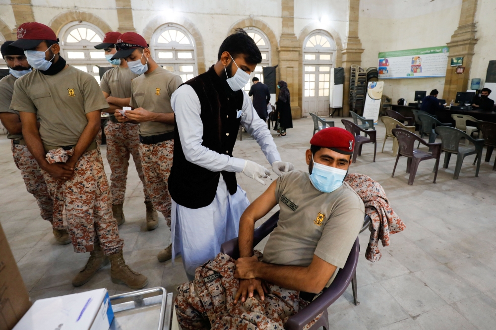 A paaramilitary soldier receives a dose of coronavirus disease (COVID-19) vaccine while others wait for their turn at a vaccination centre in Karachi, Pakistan, January 21, 2022. REUTERS/Akhtar Soomro
