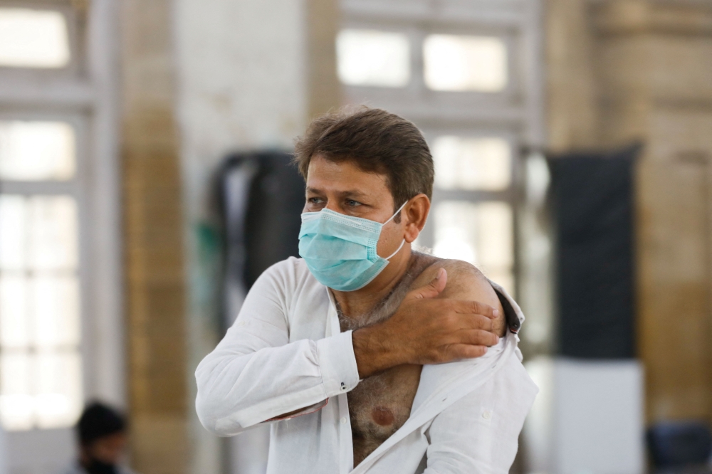 A man rubs his arm after he received a dose of coronavirus disease (COVID-19) vaccine at a vaccination centre in Karachi, Pakistan, January 21, 2022. REUTERS/Akhtar Soomro
