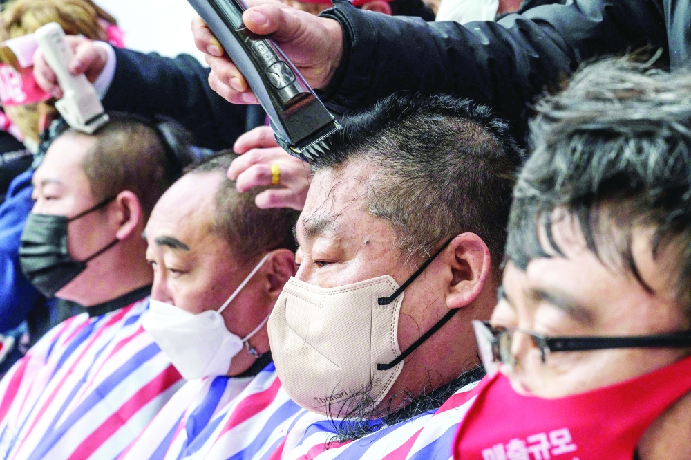 Small business owners have their heads shaved during a protest against the government's Covid-19 social distancing measures in Seoul. - AFP