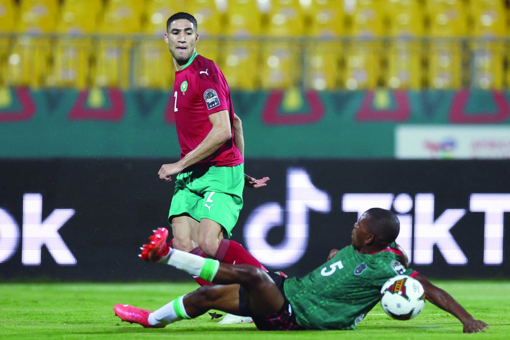 Morocco's defender Achraf Hakimi (back) is challenged by Malawi's defender Denis Chembezi during the Africa Cup of Nations (CAN) 2021 round of 16 football match between Morocco and Malawi at Stade Ahmadou-Ahidjo in Yaounde on January 25, 2022.  (Photo by Kenzo Tribouillard / AFP)

