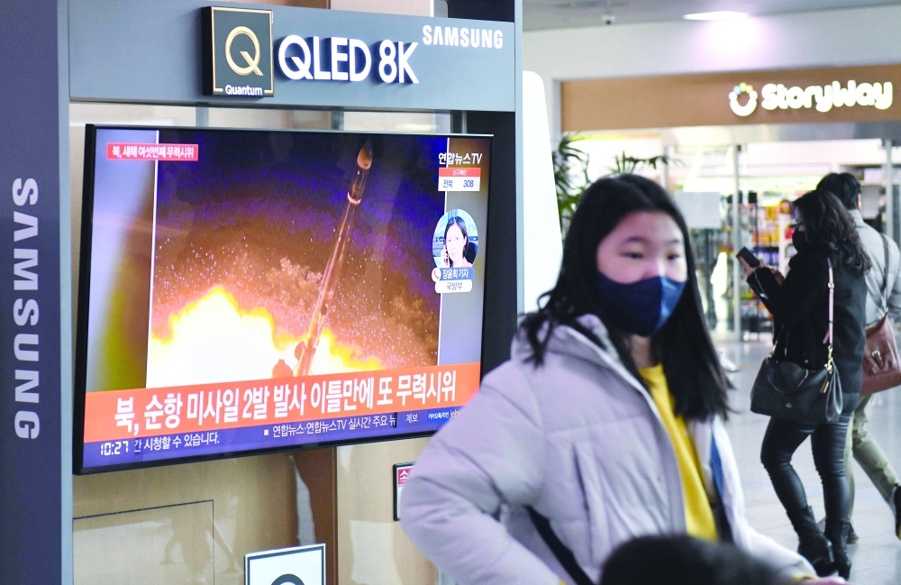 People walk past a television screen showing a news broadcast with file footage of a North Korean missile test at a railway station in Seoul on Thursday. - AFP

