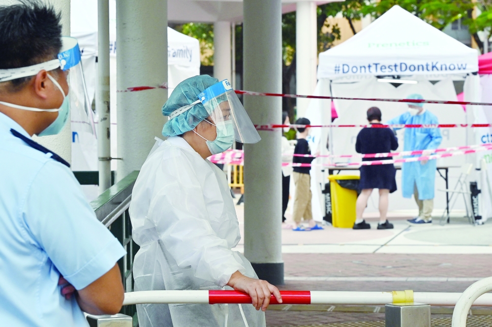 Officials in protective closing work at a Covid-19 testing station following a recent cluster of coronavirus cases, at the Kwai Chung housing estate in Hong Kong on Thursday. - AFP