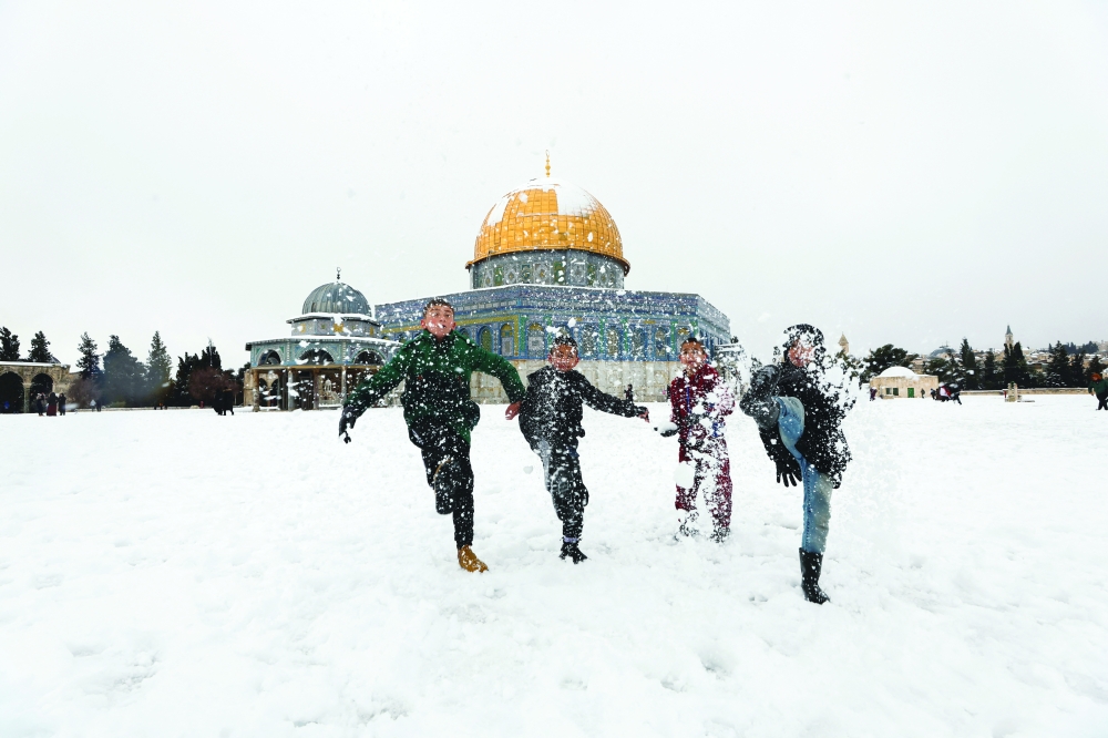 Children kick snow by the Dome of the Rock, located in Jerusalem's Old City, during a snowy morning in Jerusalem's Old City, on Thursday. - Reuters