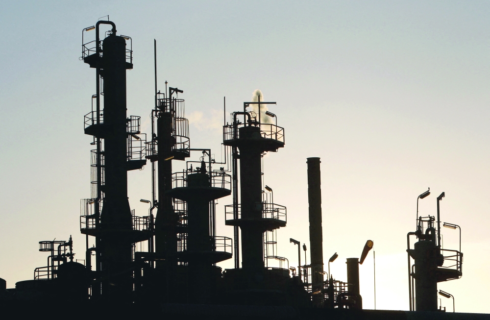 FILE PHOTO: Towers and smokestacks are silhouetted at an oil refinery in Melbourne