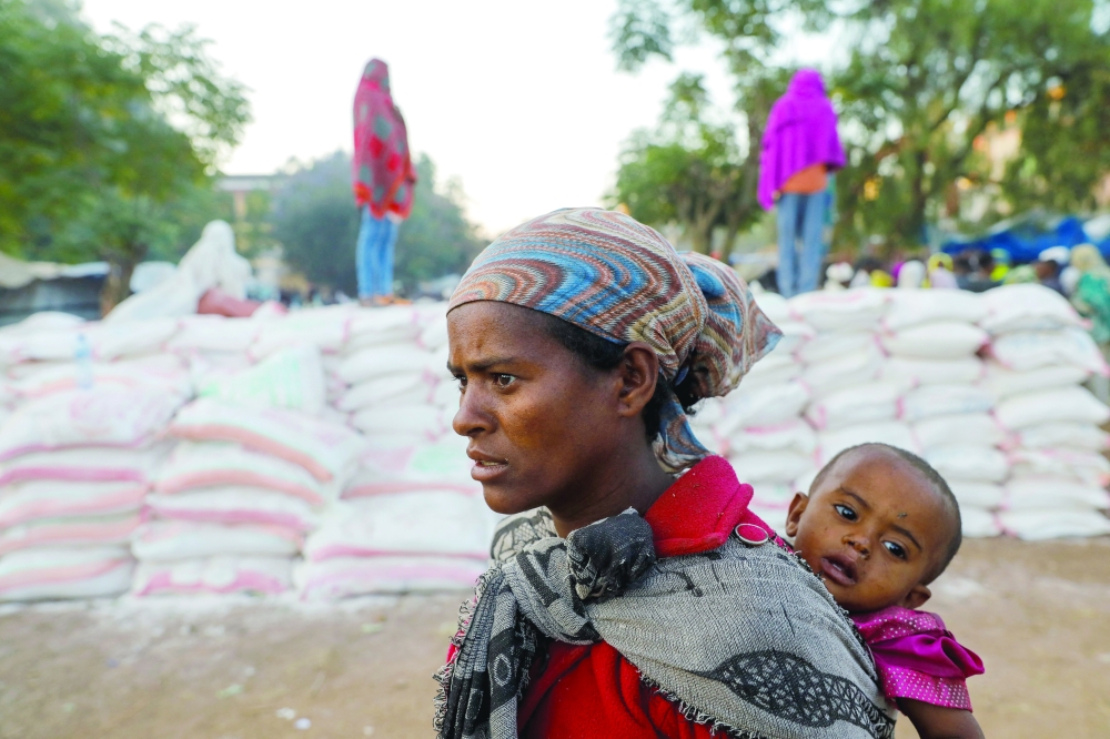 A woman carries an infant as she queues in line for food, at the Tsehaye primary school, which was turned into a temporary shelter for people displaced by conflict, in the town of Shire, Tigray region, Ethiopia. - Reuters file photo