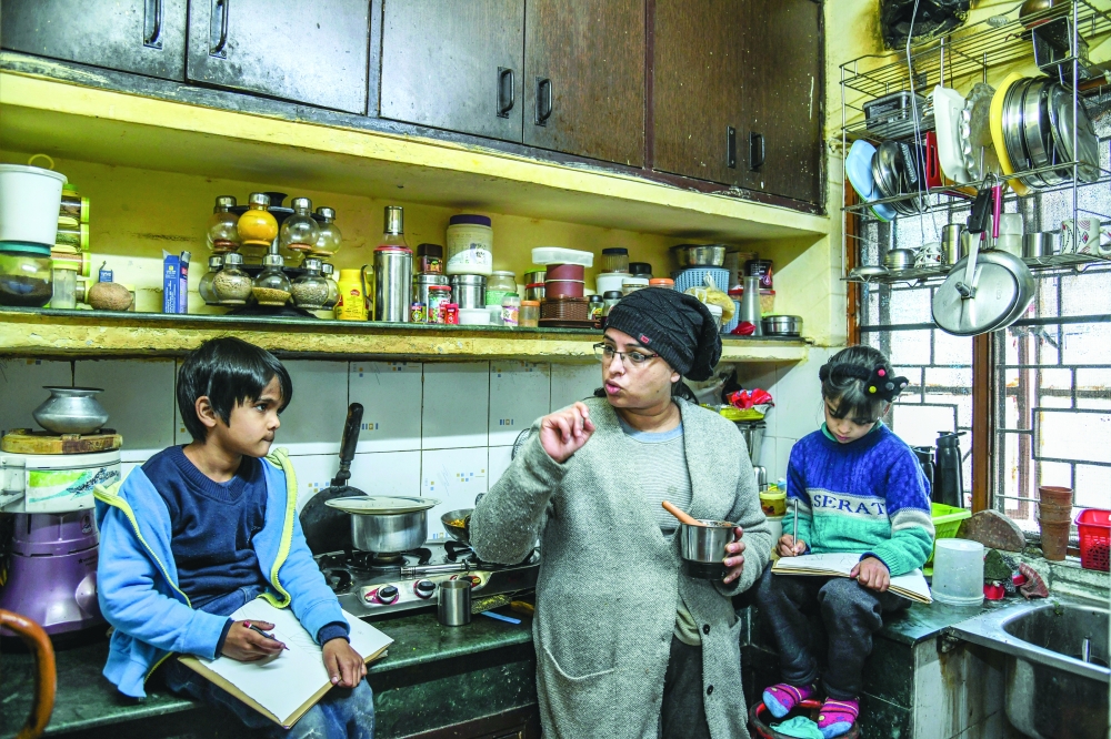 Anuradha Maindola cooks while overseeing the schoolwork of her children Rudra and Ishita, who Maindola estimates have spent only about a month attending school in person since March 2020, at their home in Dehradun.
