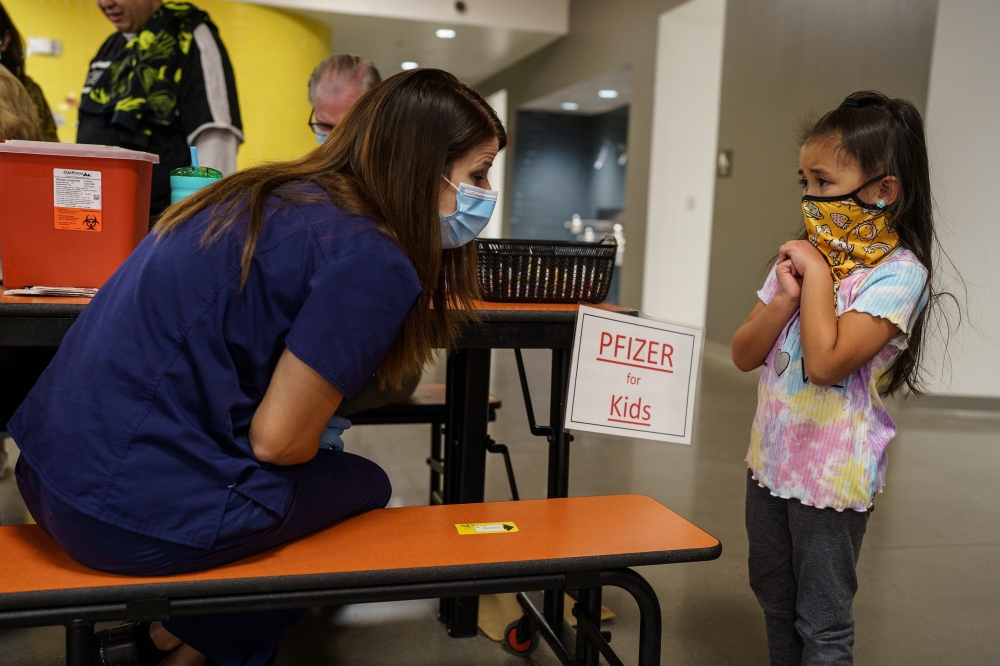 Mila Pagador, 5, speaks to registered nurse Ashley Bean before she receives her dose of the Pfizer-BioNTech COVID-19 vaccine