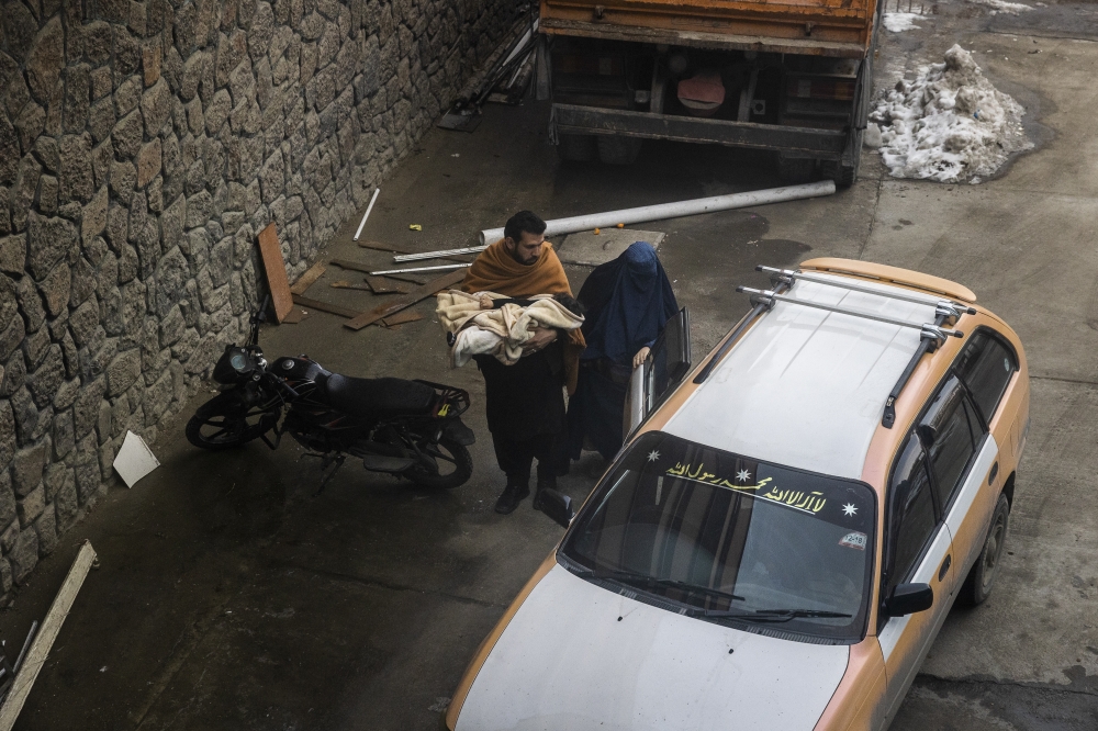 A mother and father arrive with a child by taxi at the Indira Gandhi Children's Hospital in Kabul, Afghanistan, Jan. 12, 2022.  (Jim Huylebroek/The New York Times)