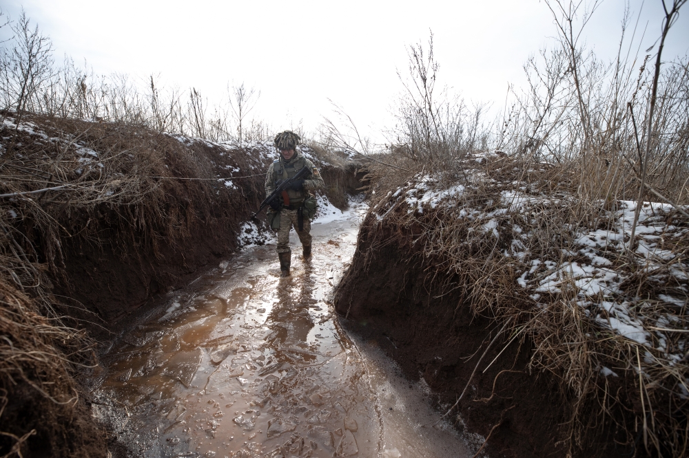 A Ukrainian army soldier walks through ice covered water in a trench at a front line position in New York, Ukraine on Monday, Feb. 7, 2022. (Tyler Hicks/The New York Times)