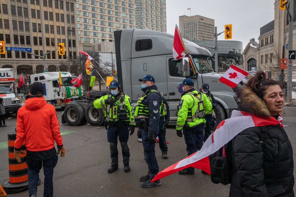 Police walk among trucks blocking streets in Ottawa, Ontario, on Friday, Feb. 11, 2022, in Canada, where protesters are demanding an end to vaccine mandates and coronavirus restrictions. (Brett Gundlock/The New York Times)