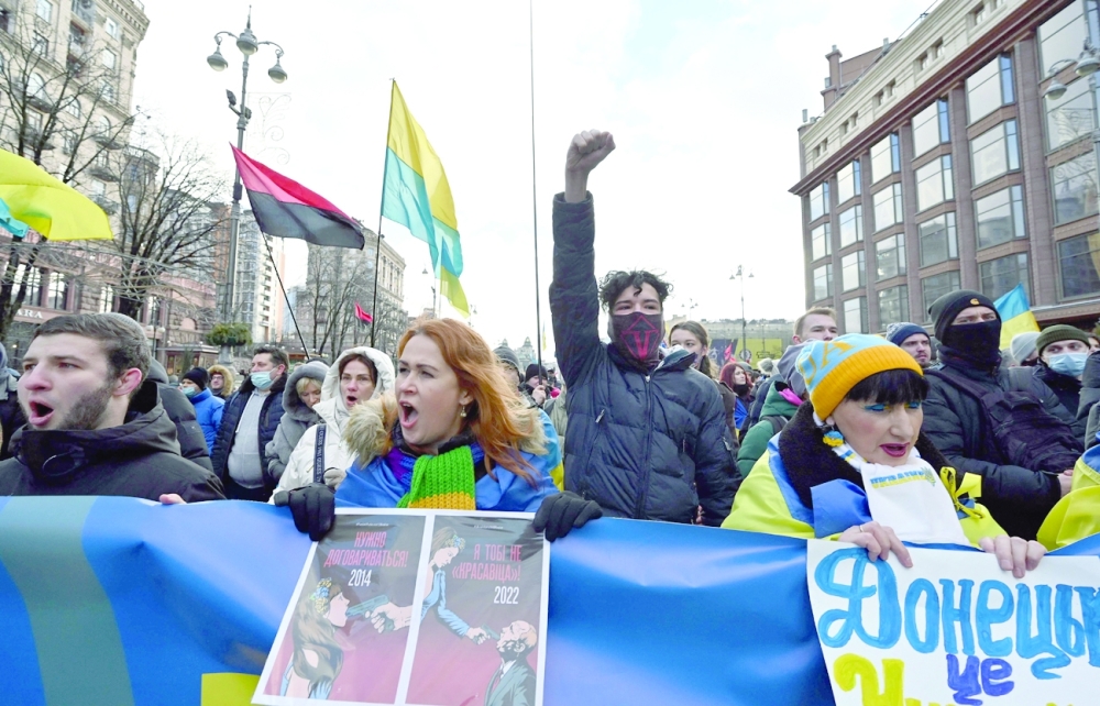 Demonstrators shout slogans as they march behind a banner which reads "Ukrainians will resist" in the colours of the national flag during a rally in Kyiv on Saturday. — AFP