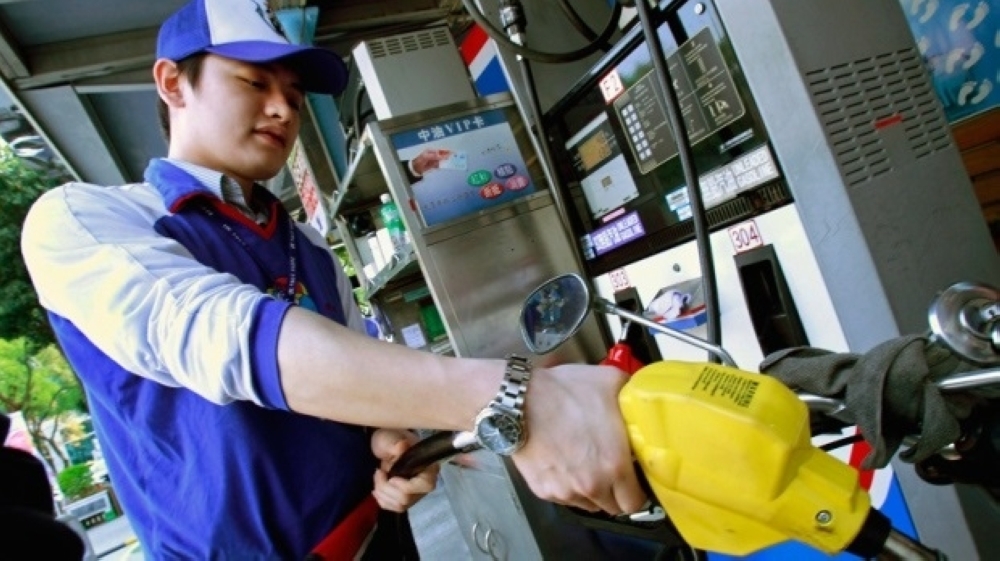 A man fills a motorcycle with gas at a station in Taipei. — AFP