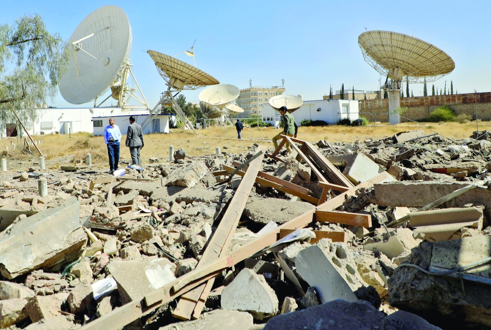 Yemeni security guards inspect the damage in the vicinity of the telecommunication ministry following overnight airstrikes by the coalition in Sanaa. - AFP

