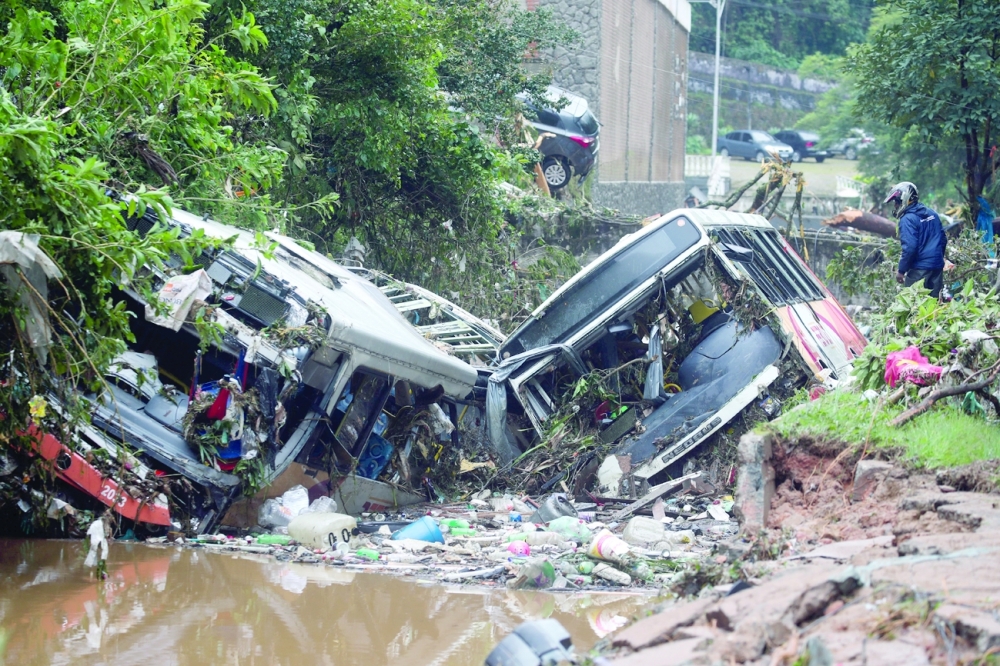 A man observes damaged public buses at a river after pouring rains in Petropolis, Brazil. - Reuters 