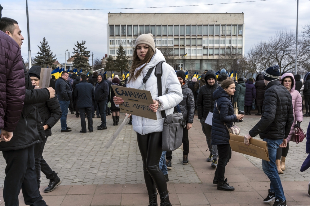 A woman holds a sign reading unity is love during a ceremony to mark Unity Day in Kherson, Ukraine, on Wednesday, Feb. 16, 2022. (Brendan Hoffman/The New York Times)