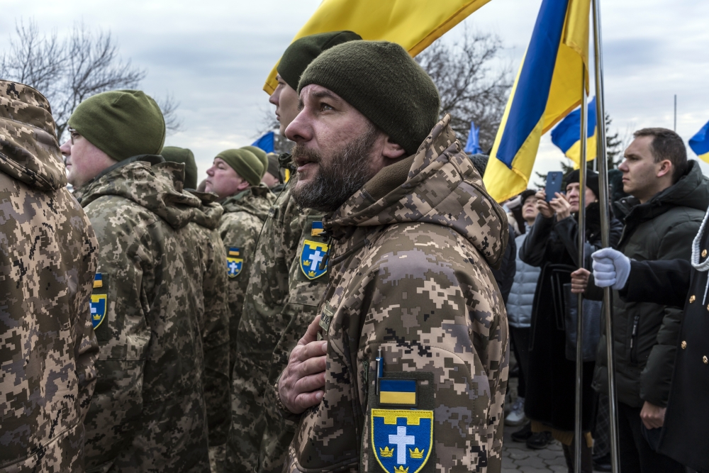 Ukrainian soldiers sing the national anthem during a ceremony to mark Unity Day in Kherson, Ukraine, on Wednesday, Feb. 16, 2022. (Brendan Hoffman/The New York Times)