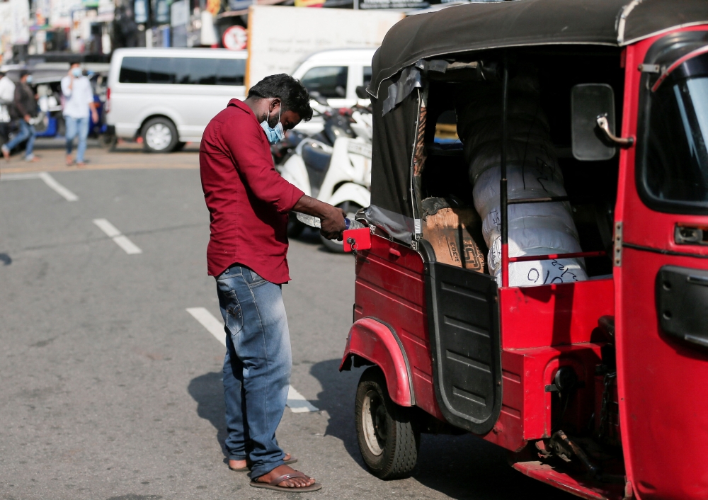 A man fills his three-wheeler with petrol from a bottle near a Ceylon Petroleum Corporation fuel station in Colombo, Sri Lanka February 21, 2022