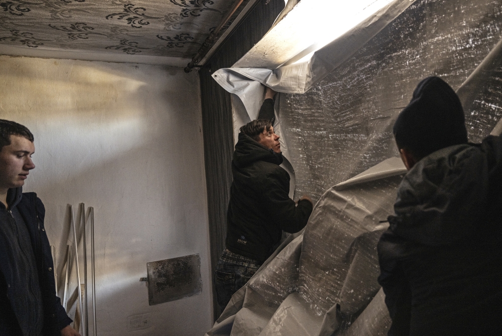 Ukrainians repair windows after residential homes were shelled a few hours earlier in the village of Vrubivka, Ukraine, Feb. 21, 2022. (Lynsey Addario/The New York Times)