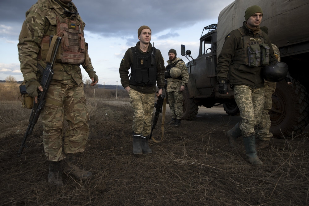 Ukrainian soldiers in front of a crater left by a mortar explosion at a front line position, which has come under recent mortar attack, in Novozvanivka, Ukraine, Feb. 21, 2022.. (Tyler Hicks/The New York Times)