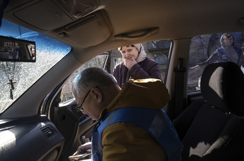 Oleksander Shestakov, with the United Nations partner organization Proliska, takes the information of villagers whose homes needed plastic sheeting and other materials for repairs hours after the village was shelled in Vrubivka, Ukraine, Feb. 21, 2022. (Lynsey Addario/The New York Times)