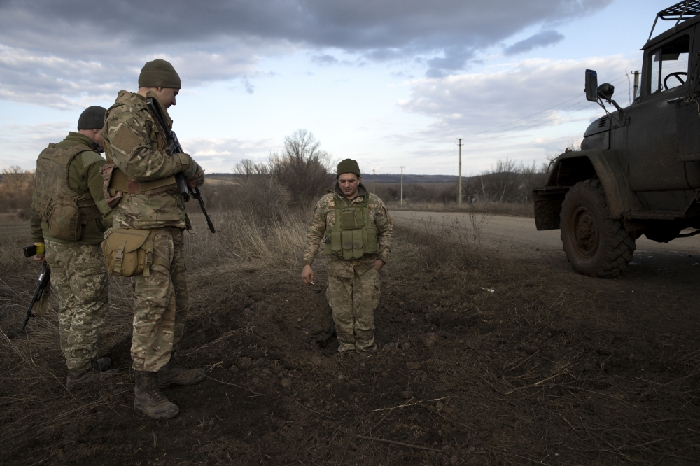 A Ukrainian soldier stands in a crater left by a mortar explosion at a front line position, which has come under recent mortar attack, in Novozvanivka, Ukraine, Feb. 21, 2022. (Tyler Hicks/The New York Times)