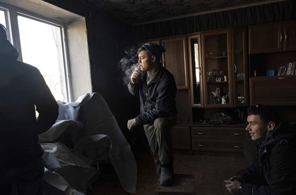 Vladimir Raspatov, center, pauses from covering windows damaged by morning shelling in the village of Vrubivka, Ukraine, Feb. 21, 2022. (Lynsey Addario/The New York Times)