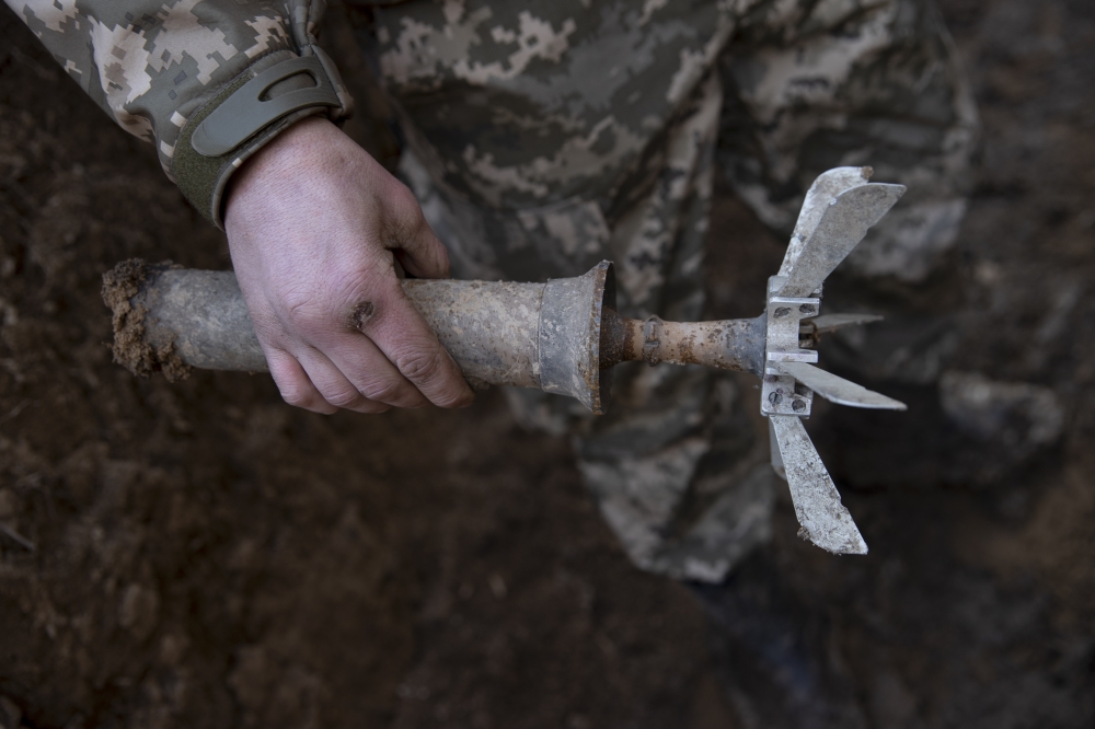 A Ukrainian soldier holds the remains of a mortar round at a front line position, which has come under recent mortar attack, in Novozvanivka, Ukraine, Feb. 21, 2022.  (Tyler Hicks/The New York Times)