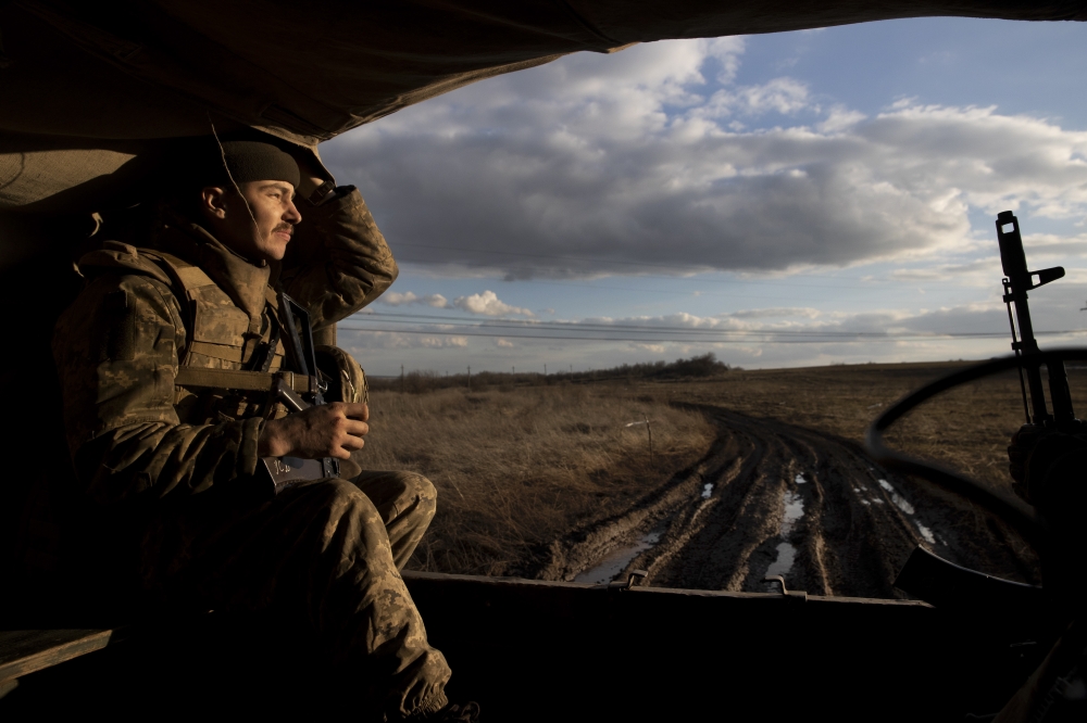Stanislav Kuzminskiy, a Ukrainian soldier, clutches a flower for his girlfriend while riding in the back of a truck at a front line position, which has come under recent mortar attack, in Novozvanivka, Ukraine, Feb. 21, 2022.  (Tyler Hicks/The New York Times)
