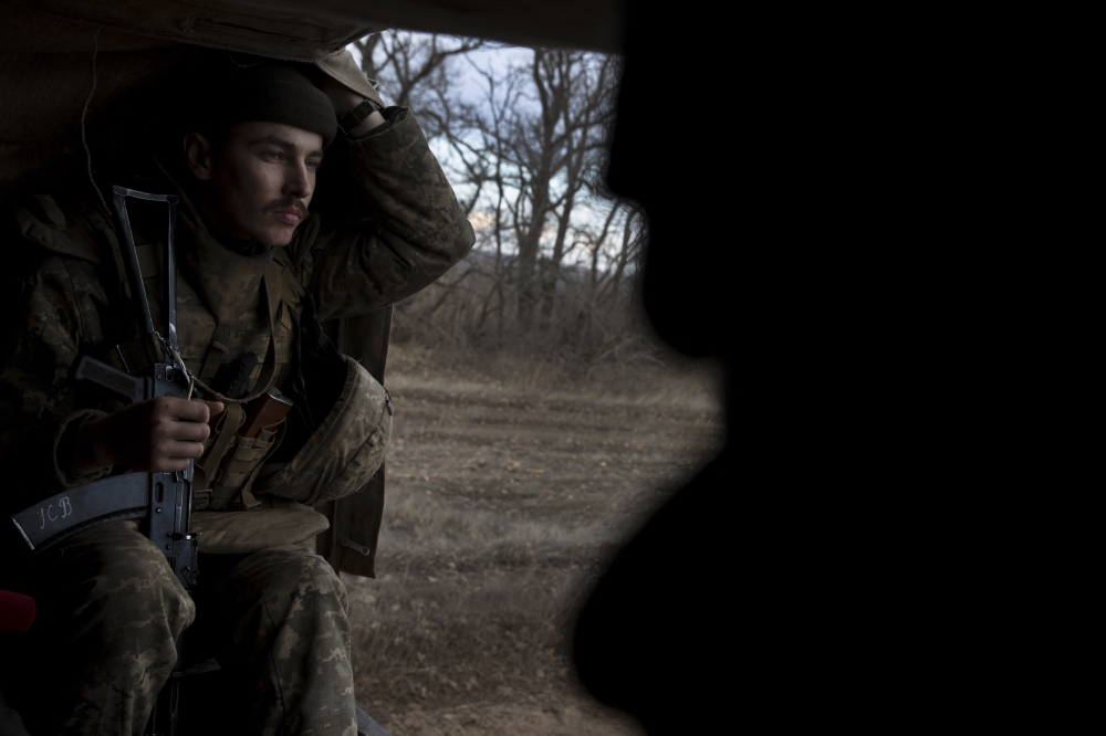 Stanislav Kuzminskiy, a Ukrainian soldier, clutches a flower for his girlfriend while riding in the back of a truck at a front line position, which has come under recent mortar attack, in Novozvanivka, Ukraine, Feb. 21, 2022.  (Tyler Hicks/The New York Times)