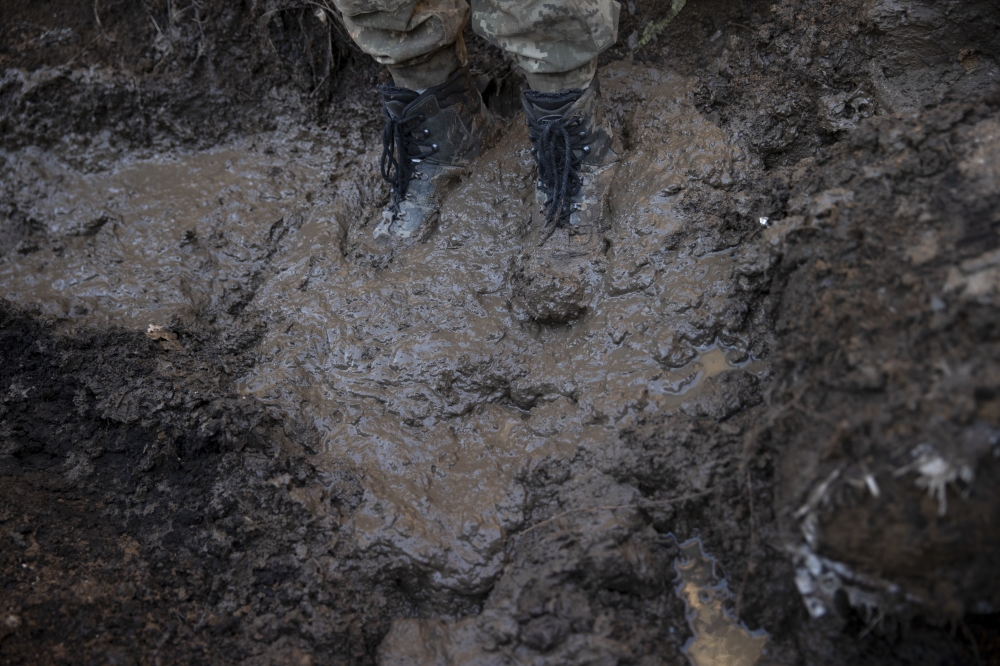 A Ukrainian soldier stands in a muddy trench at a front line position, which has come under recent mortar attack, in Novozvanivka, Ukraine, Feb. 21, 2022. (Tyler Hicks/The New York Times)
