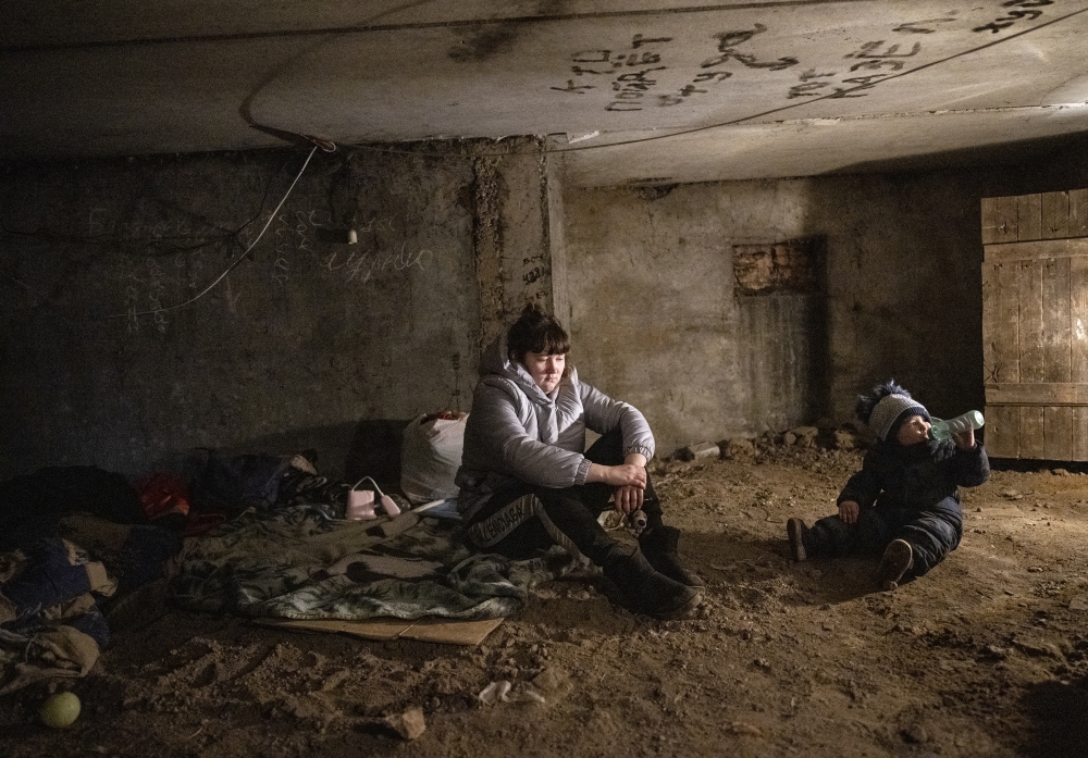 Kristina Makarenko sits in a shelter with her two-year-old son, Anton, after hearing separatists had returned to their artillery positions in the village of Vrubivka, Ukraine, Feb. 21, 2022. (Lynsey Addario/The New York Times)