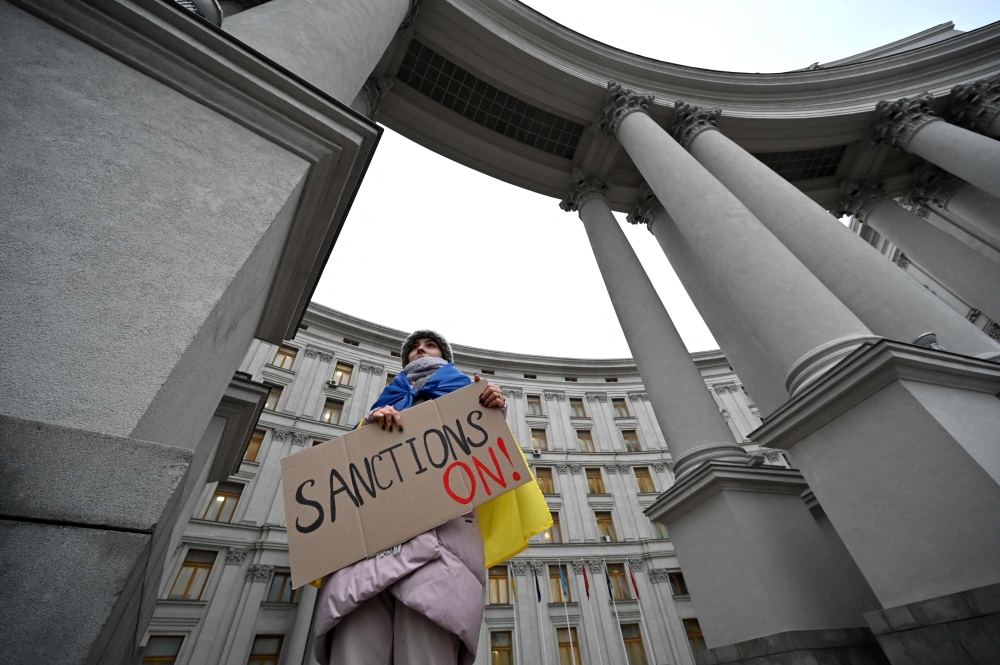 A protester holds a placard during a rally outside of Ukrainian Ministry of Foreign Affair in Kyiv on February 21, 2022 during the action "Turn sanctions ON!". 
