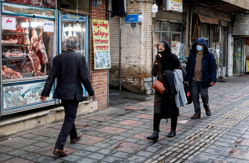 People walk past a butcher's shop in the south of Iran's capital Tehran  (Photo by AFP)

