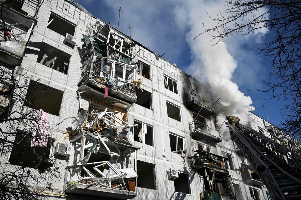 Firefighters work on a fire on a building after bombings on the eastern Ukraine town of Chuguiv on February 24