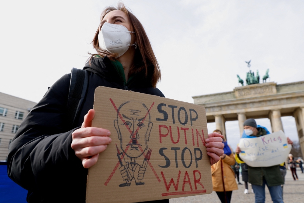 People hold signs as they demonstrate at Brandenburg Gate