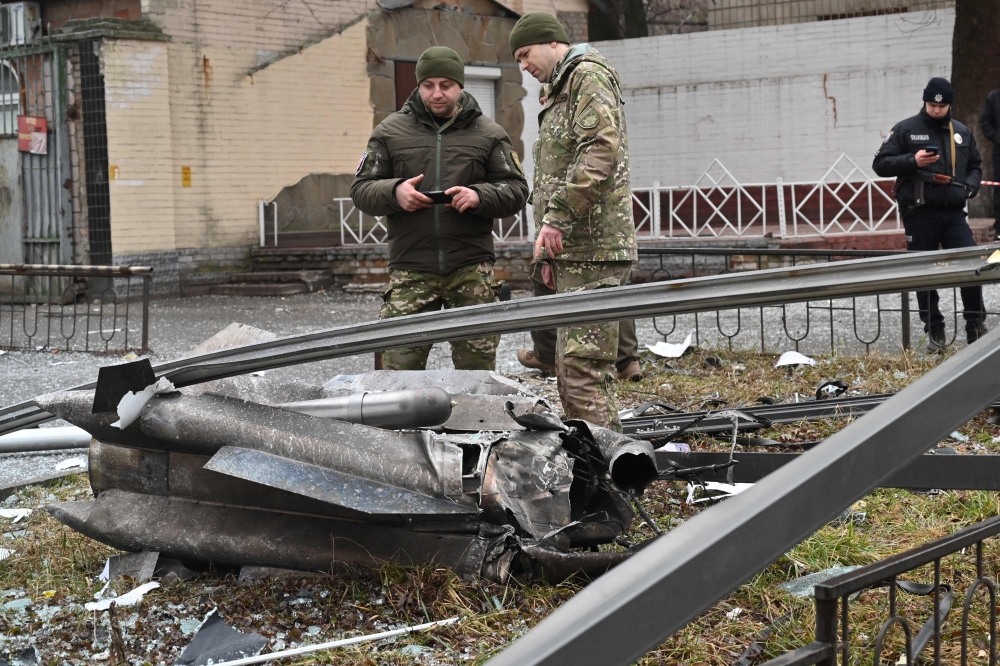 Police and security personnel inspect the remains of a shell in a street in Kyiv on February 24, 2022. 