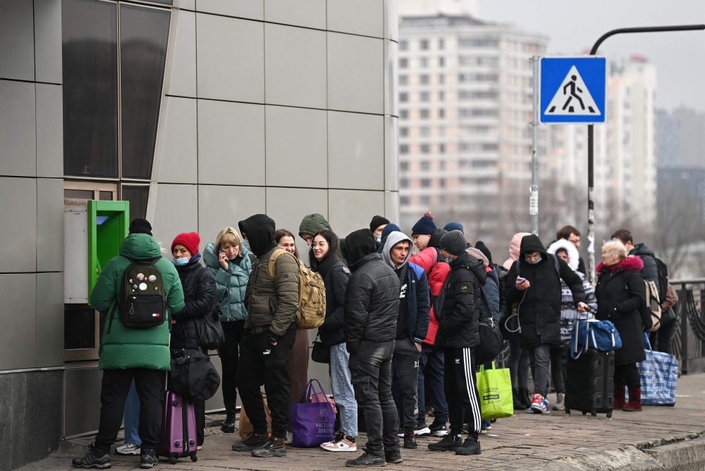 People line up to withdraw money at a cash dispenser in Kyiv in the morning of February 24, 2022. 